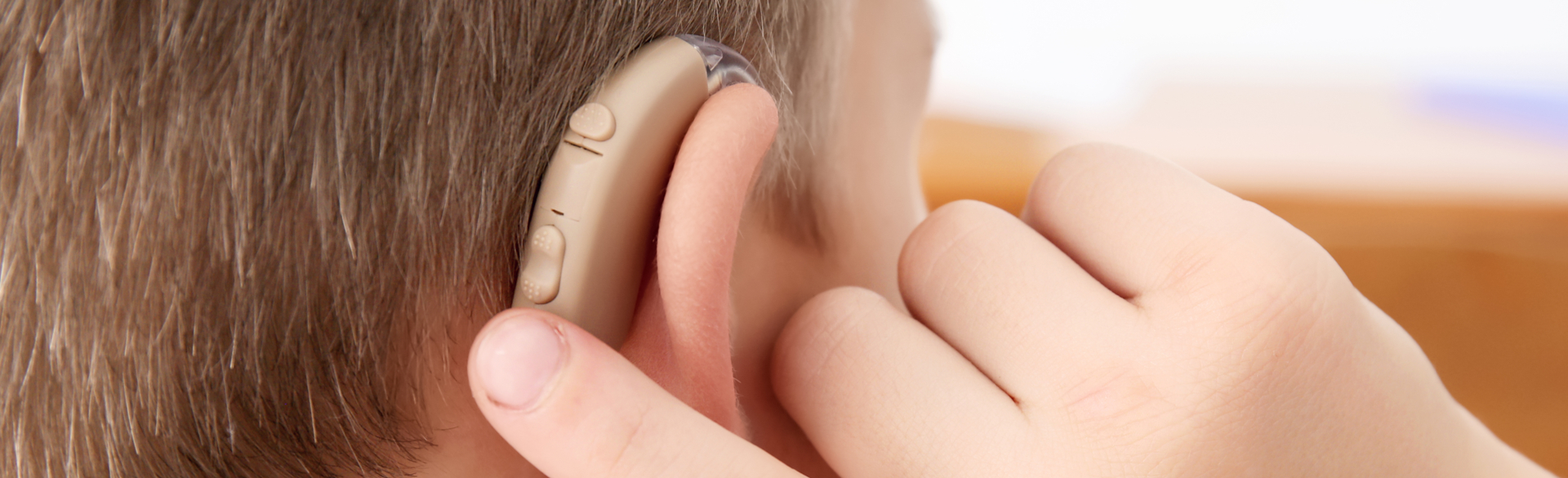 Child adjusting hearing aid in right ear