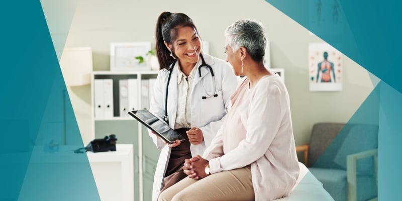 a woman doctor looks over charts with an older woman patient