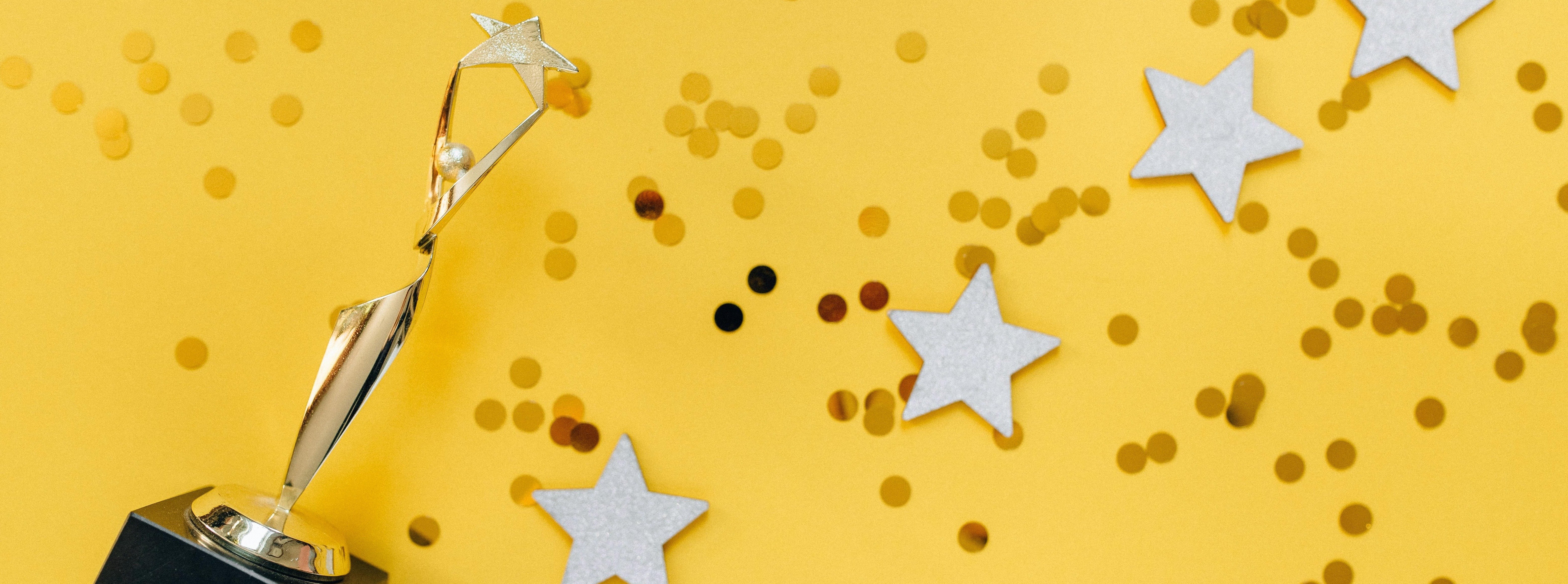 Image of trophy on yellow background with confetti. Stock photo.