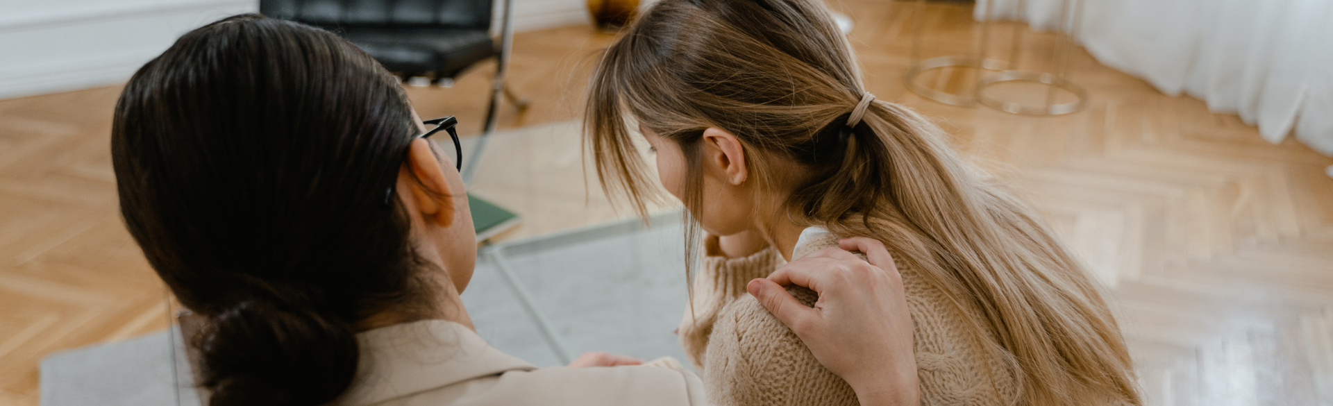 A friend or provider comforts a long-haired patient, both their backs are to the camera